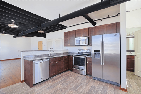 A kitchen with a stainless steel refrigerator, oven, and sink.